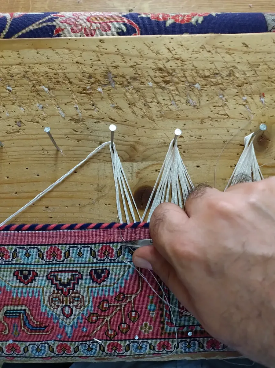 Restauration in Handarbeit: neue Knoten werden an der Kette geknüpft